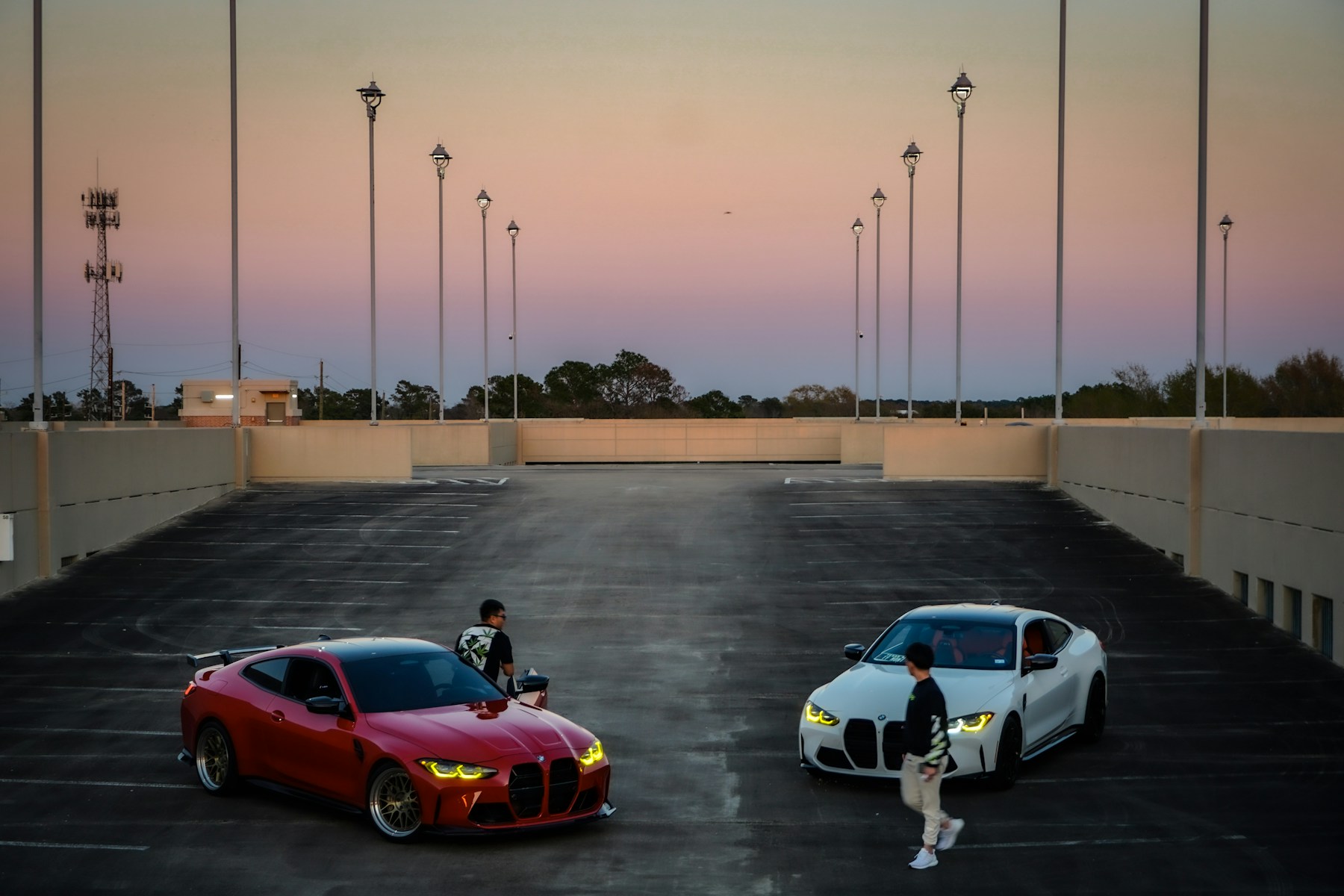 Modified BMW coupes at a rooftop gathering at sunset